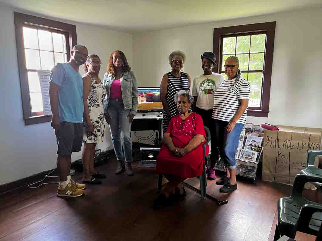 A family gathering in a cozy room with natural light and a piano.