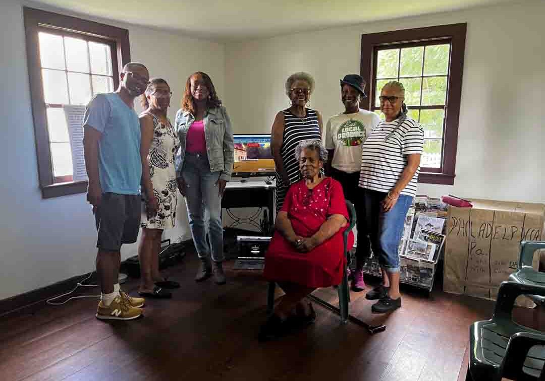 A family gathering in a cozy room with natural light and a piano.